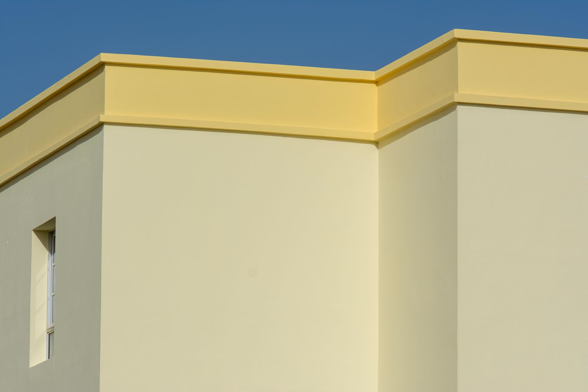 a yellow building with a blue roof and a white wall
